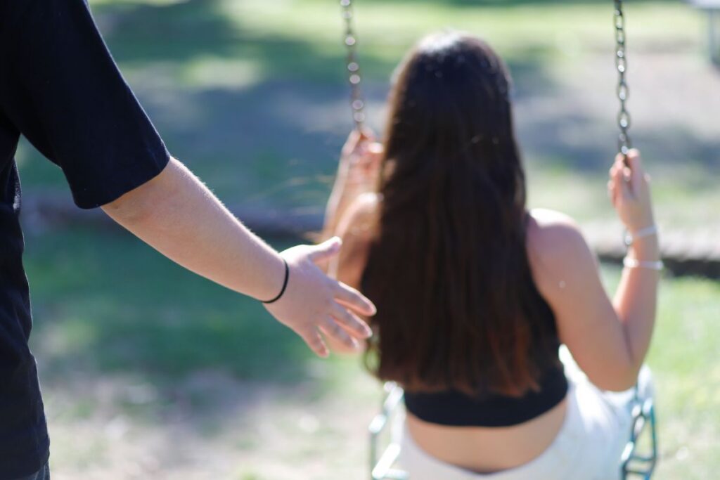 Imagen de una persona hamacando a una adolescente.