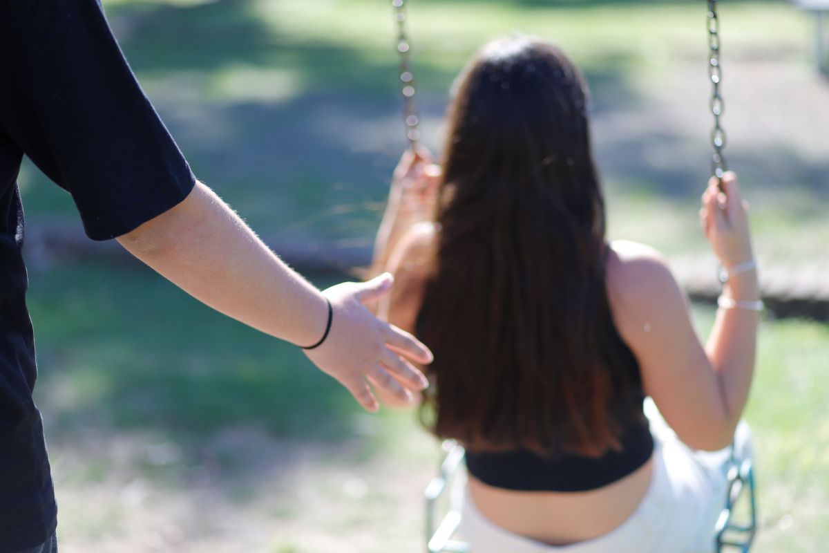 Imagen de una persona hamacando a una adolescente.